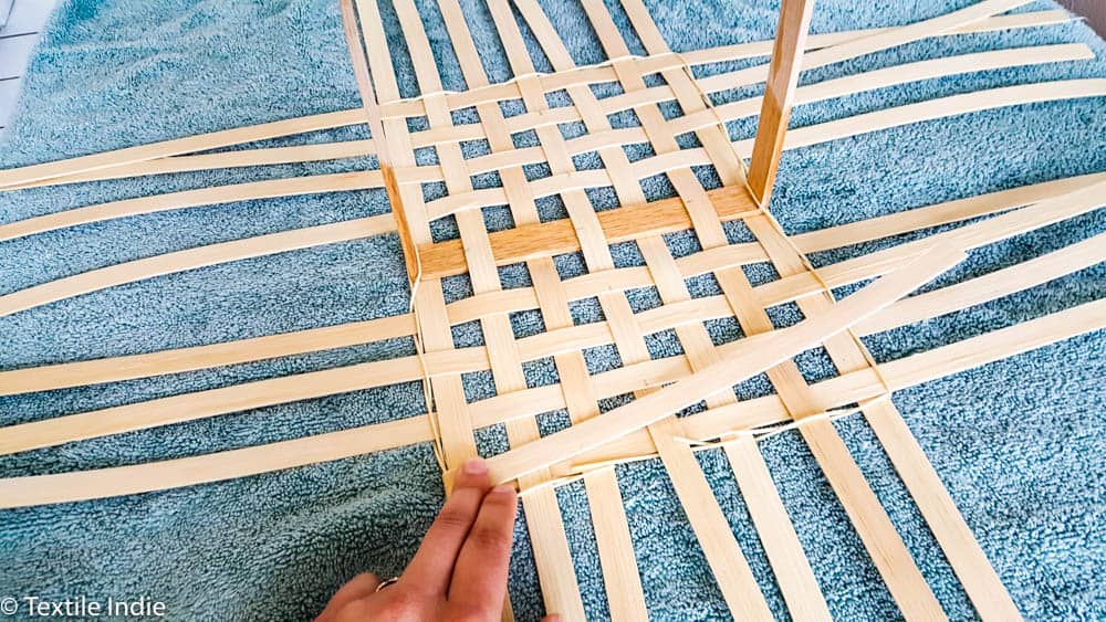 crimping the corner of the twine at the base of a basket