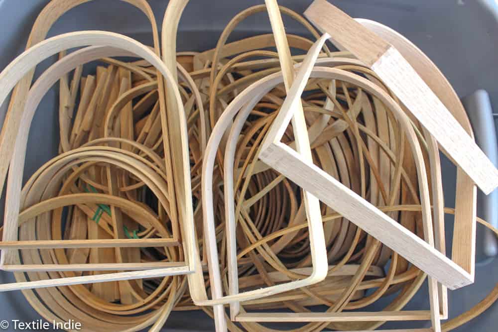 Bin of assorted basket handles for handwoven baskets.