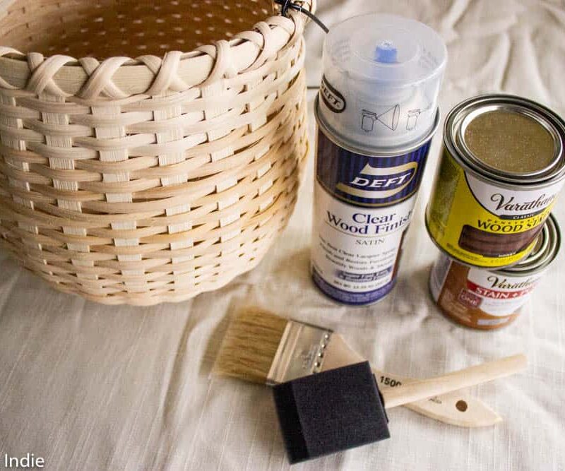 A basket, brushes and some cans of wood stain on a piece of fabric