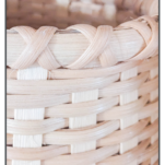 Close-up photo highlighting the intricate cross-stitch rim of a handcrafted basket. The X-shaped pattern creates a decorative and secure binding around the basket's edge.