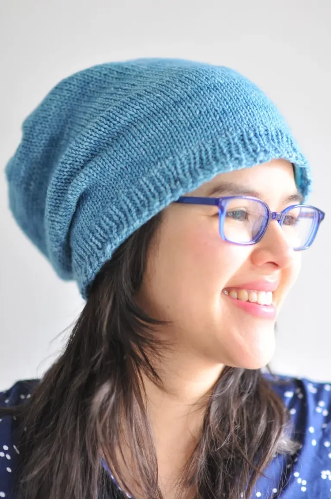 blue touque knit hat on a dark-haired woman with blue eyeglasses 