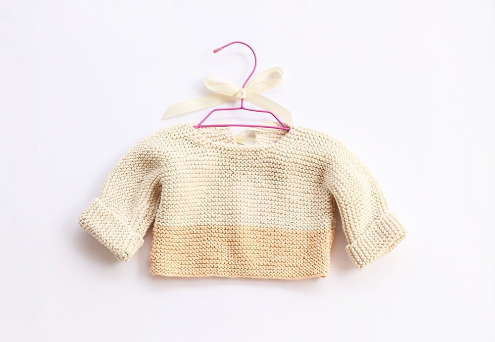 yellow color block baby sweater on a pink hanger