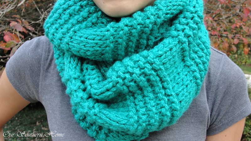 Turquoise knit infinity scarf around the neck of a woman