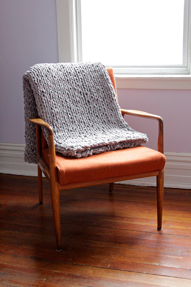 beautiful luxury grey knit throw blanket folded over a brown leather chair