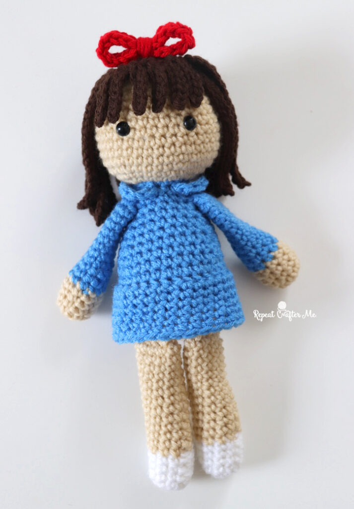 crochet doll with a red bow and a blue dress