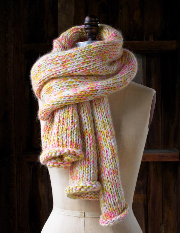 pink, yellow, and white confetti yarn made into a swiling knit scarf, wound around a sewing form