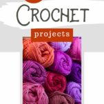 A stack of bright purple, orange, pink, and red yarn skeins are piled on top of one another.