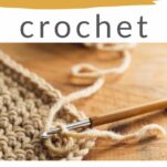 A crochet hook in the middle of a project, a small piece of tan crochet work in the corner of the image.