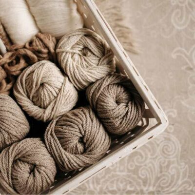 box filled with balls of yarn in muted cream and tan colors against a tan bandana fabric