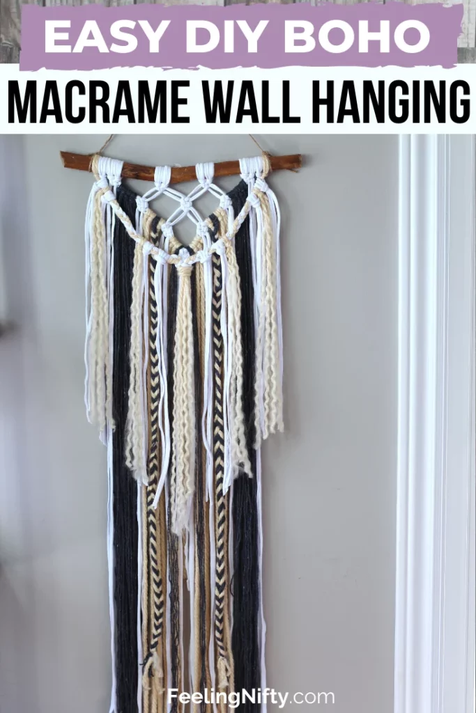 A bohemian style macrame wall hanging in black, cream, and white hanging from a rustic stick