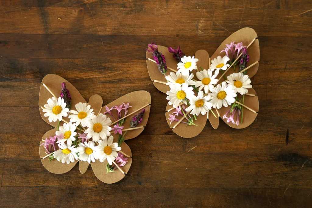 Pieces of cardboard cut into butterflies with flowers rubber banded on 