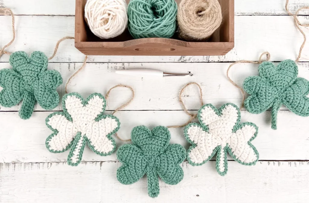 The Knotted Nest green and white shamrock crochet garland against a shiplap background 
