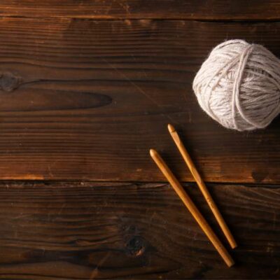 a cream ball of yarn and crochet hooks set on a wooden table