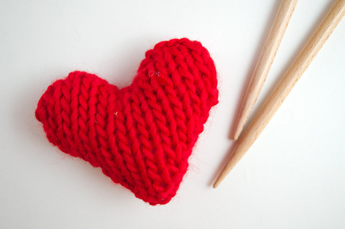 A red knit heart with bamboo knitting needles 