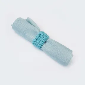 Sunflower Cottage Crochet napkin ring in turquoise on a light blue linen napkin