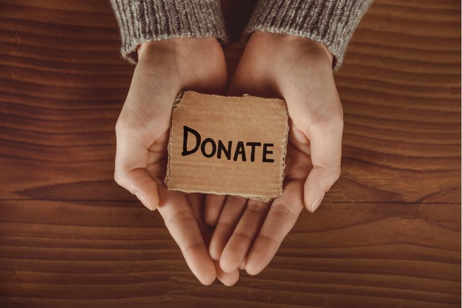 A set of hands holding a cardboard square that says donate 