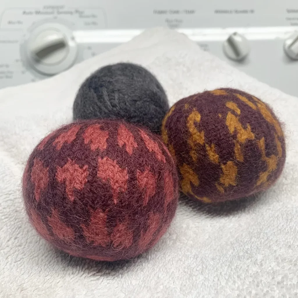 three wool dryer balls sitting on a white blanket 