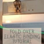 Close-up of a sewing machine presser foot, threaded with white yarn, ready to go.